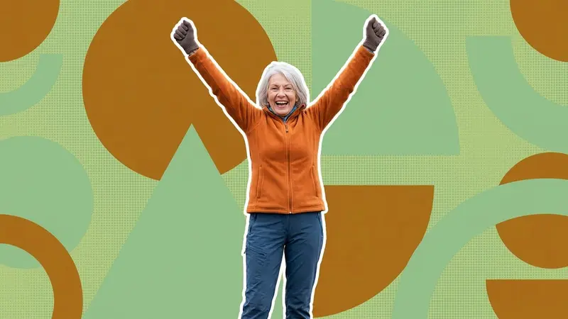 A joyful older woman in sporty clothes with her arms raised